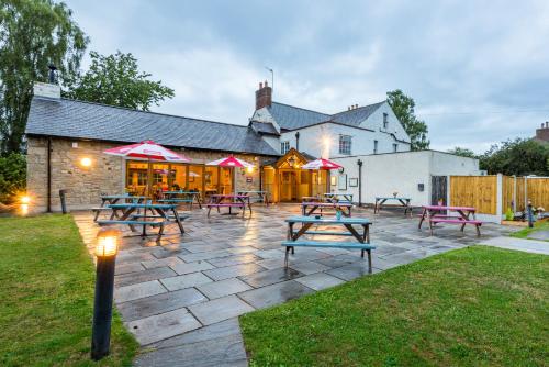 a patio with picnic tables in front of a building at The Queens in Carlisle
