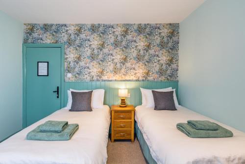 two twin beds in a room with blue walls at The Queens in Carlisle