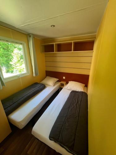 2 camas en una habitación pequeña con ventana en mobil home en Saint-Chéron