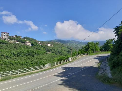 un camino vacío con una valla a un lado de una montaña en Newsuit2023 en Trabzon