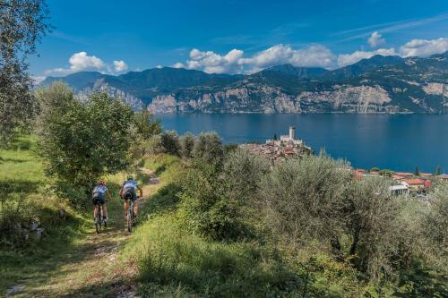 two people riding bikes on a trail next to a body of water at Natur Resort Panorama in Malcesine