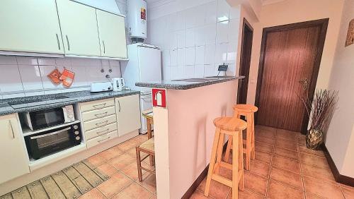 a kitchen with white cabinets and a counter with stools at Casa Gouveia in Porto Santo