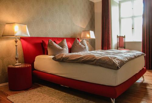 a bedroom with a bed with a red headboard and two lamps at Gutshaus Gevezin in Gevezin