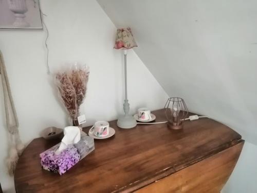 uma mesa de madeira com duas chávenas e um candeeiro em Chambre d'hôtes La Montjoie em La Souris