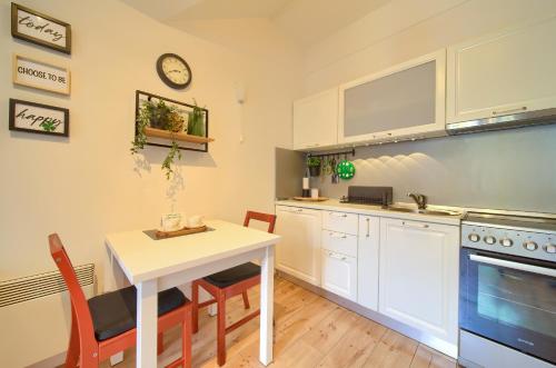 a kitchen with white cabinets and a table and chairs at Studio Apartman Roxy in Fužine