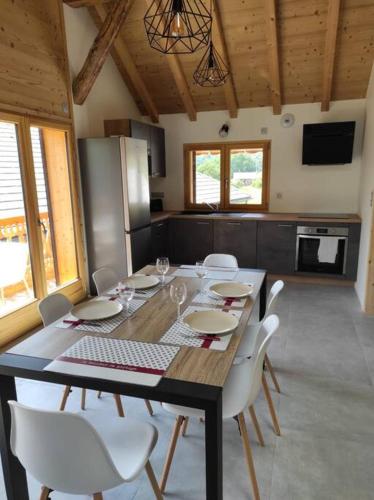 une salle à manger avec une table et des chaises blanches dans l'établissement L'échappée Belle en Montagne - site location-chalet, à Mieussy