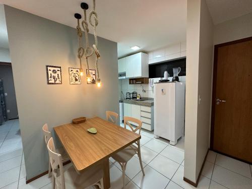 uma cozinha e sala de jantar com uma mesa de madeira e cadeiras em 02 QUARTOS, a 200 metros da PRAIA de PAJUÇARA em Maceió