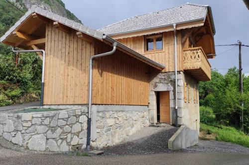 a wooden house with a porch and a stone wall at L'échappée Belle en Montagne in Mieussy