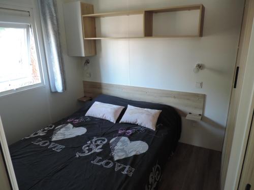 une petite chambre avec un lit dans une petite pièce dans l'établissement Mobil home Lège Cap Ferret Camping 4 étoiles Les Viviers, à Lège-Cap-Ferret