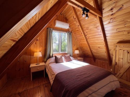 a bedroom with a bed in a wooden cabin at Los Plátanos cabañas & suites in Moreno