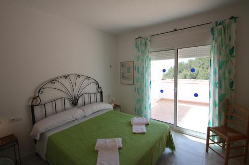 um quarto com uma cama verde e uma porta de vidro deslizante em Sesam - sea view villa with private pool in Moraira em Moraira