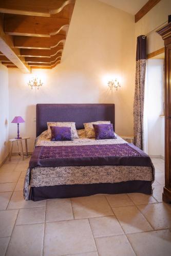 a bedroom with a large bed with purple sheets and pillows at Les Chènevottes au Hameau 1936 in Cherveux