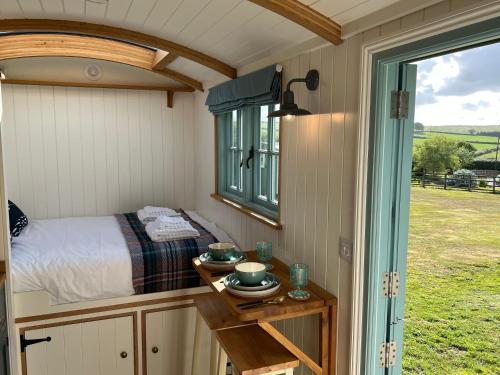 a small bedroom with a bed and a table at Toms Hut and Robins Rest Shepherd Huts near Wadebridge in Wadebridge