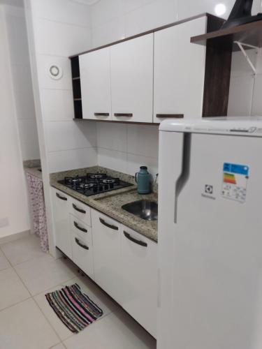 eine weiße Küche mit einer Spüle und einem Kühlschrank in der Unterkunft Apto a 300 metros da Canção Nova. Condomínio da Fé in Cachoeira Paulista
