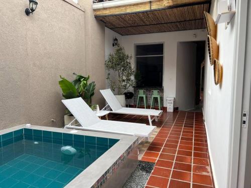 une terrasse avec une piscine et deux chaises blanches dans l'établissement Nueva en San Antonio Cali, La casa de Toña, à Cali