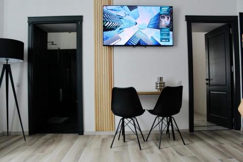 Ein Zimmer mit zwei Stühlen und einem Tisch, an dessen Wand ein Fernseher hängt. in der Unterkunft Ted’s one in Ocna-Mureşului