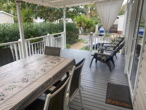 a wooden deck with a table and chairs on a house at Mobil Home Valras Plage in Valras-Plage