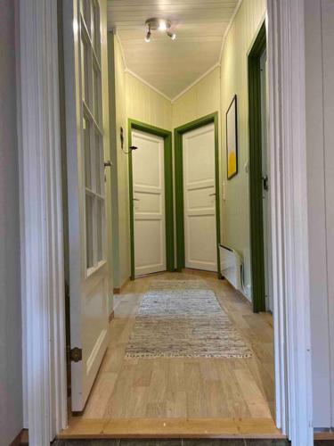 a hallway with three white doors and a rug at Frittliggende hytte i flott turterreng in Molde