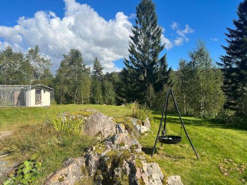 a rock in a field next to a tree at Frittliggende hytte i flott turterreng in Molde