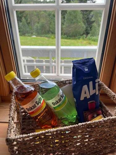 a basket with two bottles of alcohol in a window at Frittliggende hytte i flott turterreng in Molde