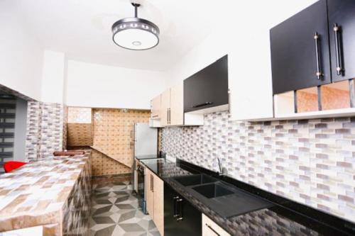 uma cozinha com armários brancos e bancadas pretas em Villa Flo Residence em Lomé