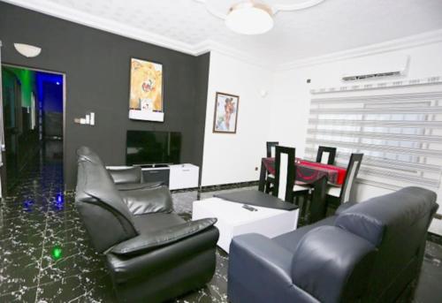a living room with black chairs and a tv at Villa Flo Residence in Lomé