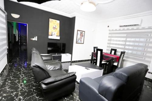 a living room with black leather chairs and a tv at Villa Flo Residence in Lomé