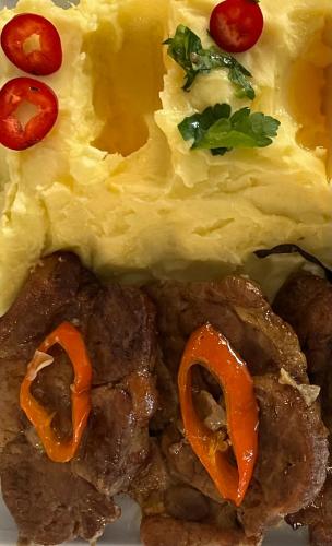 a plate of food with meat and eggs and tomatoes at Pensiunea Deceneu in Slănic
