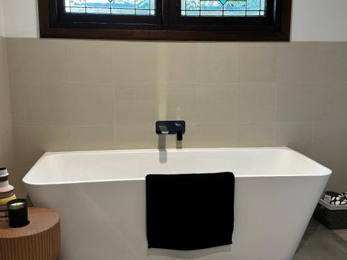 a white bath tub with a black towel on it at Tranquilo Daylesford in Daylesford