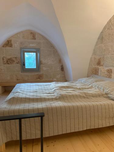 Ce lit se trouve dans un dortoir doté d'une fenêtre. dans l'établissement La Piccola Tufaia, à Fasano