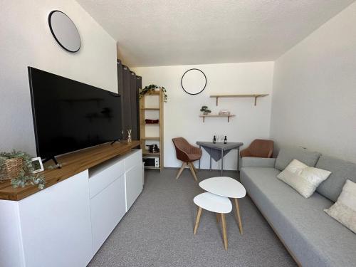 a living room with a couch and a flat screen tv at Studio Apartment BKK in Bad Kleinkirchheim