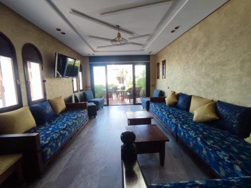 a living room with blue couches and a tv at Beach House in KSAR RIMAL in Marina Smir