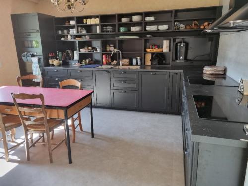 une cuisine avec des armoires noires, une table et des chaises dans l'établissement Chambre dans maison à partager, à Talensac