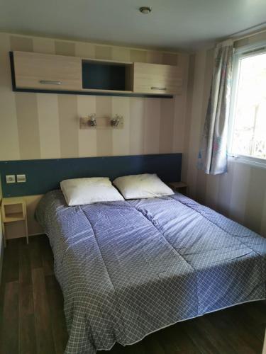 une chambre avec un lit avec une couette bleue et une fenêtre dans l'établissement Mobile Home ~ Parc des Roches, à Saint-Chéron