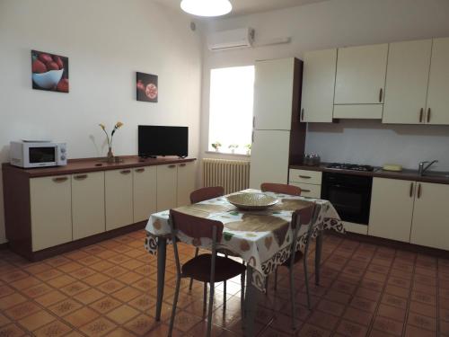 eine Küche mit einem Tisch und Stühlen sowie eine Küche mit weißen Schränken in der Unterkunft "Babbo" Nicola in Salve