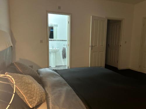 a bedroom with a bed and a bathroom with a sink at Entire 3 bedroom deluxe house in Cleckheaton