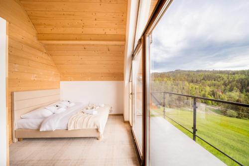 een slaapkamer met een bed en een groot raam bij Domki Wilcze Pole in Waksmund
