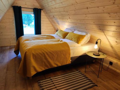 Bett in einem Zimmer mit einer Holzwand in der Unterkunft Widok na Śnieżkę - domki całoroczne in Łomnica