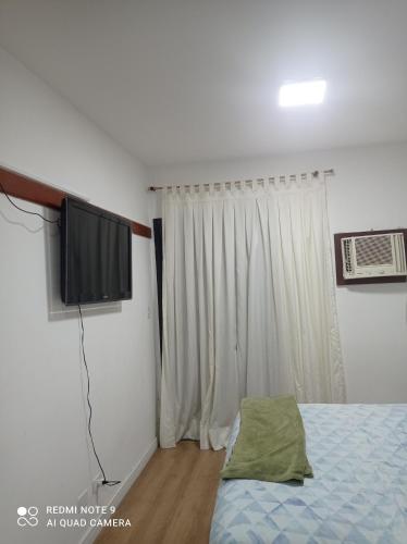 a bedroom with a bed and a flat screen tv at Flat Palladim in São Vicente