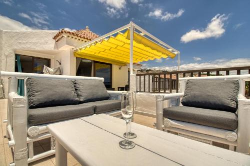 patio z 2 krzesłami i stołem ze szklanką wina w obiekcie Luxury Penthouse Sea View Jacuzzy & pool wiffi free w mieście Playa Fañabe