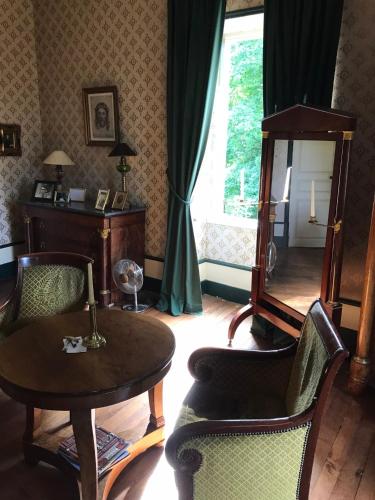 - un salon avec une table, des chaises et un miroir dans l'établissement Chateau de Vesset, à Tréteau