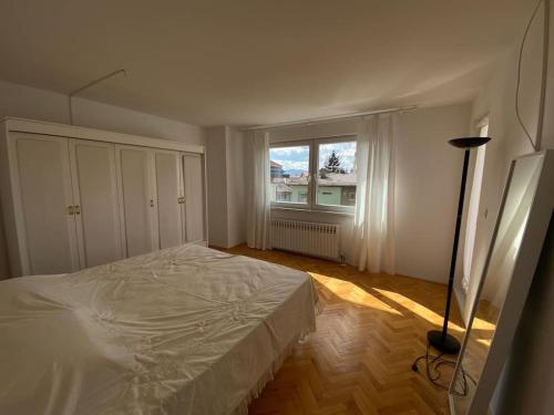 a white bedroom with a bed and a window at Downtown House with garden in Sarajevo