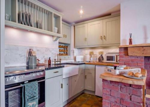 a kitchen with white appliances and a brick wall at Carpenters Cottage Quirky home Seaside town in Minehead