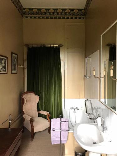 une salle de bain avec un rideau vert, une chaise et un lavabo dans l'établissement Chateau de Vesset, à Tréteau