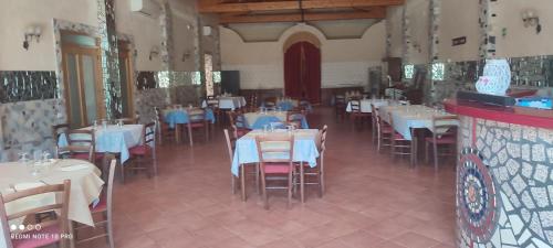 un restaurante con mesas blancas y sillas con mesas azules en alloggio greenpark, en Milazzo