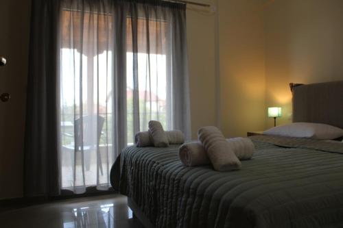 1 dormitorio con 1 cama con 2 almohadas y ventana en Electra Maisonette with Garden near Sea, en Kamárai