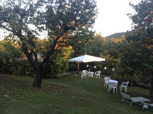 un groupe de tables et de chaises sous un parapluie blanc dans l'établissement Charming Villa in Monferrato, à Camino