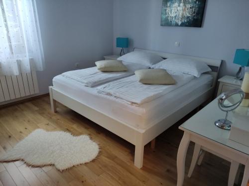 un letto con lenzuola e cuscini bianchi in una camera da letto di Apartman Roža a Matulji (Mattuglie)