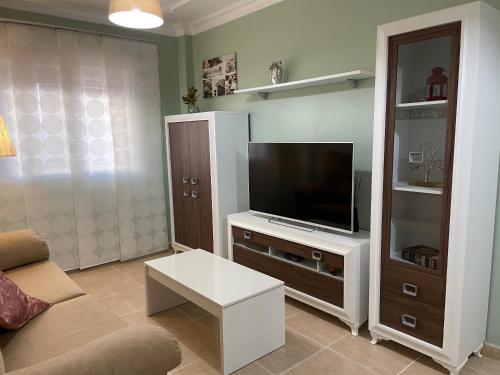 uma sala de estar com televisão num centro de entretenimento branco em Esencias Azahar em Chiclana de la Frontera