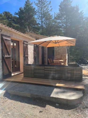 a small house with an umbrella on a deck at Les rocailles in Valderoure